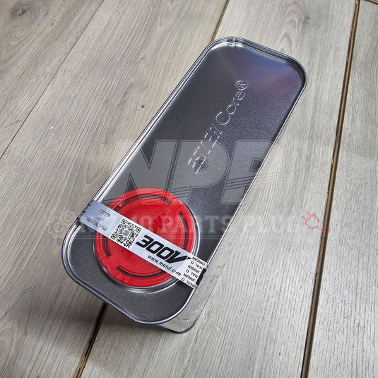 Red circular object with a label inside a metallic case on a wooden surface