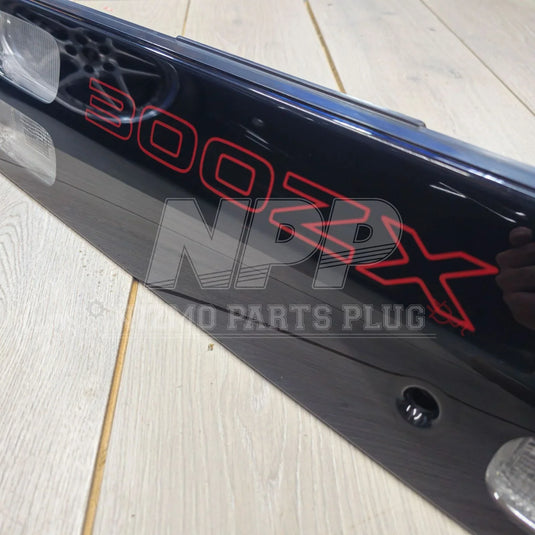 Nissan 300ZX rear tail light panel with red lettering on a wood floor