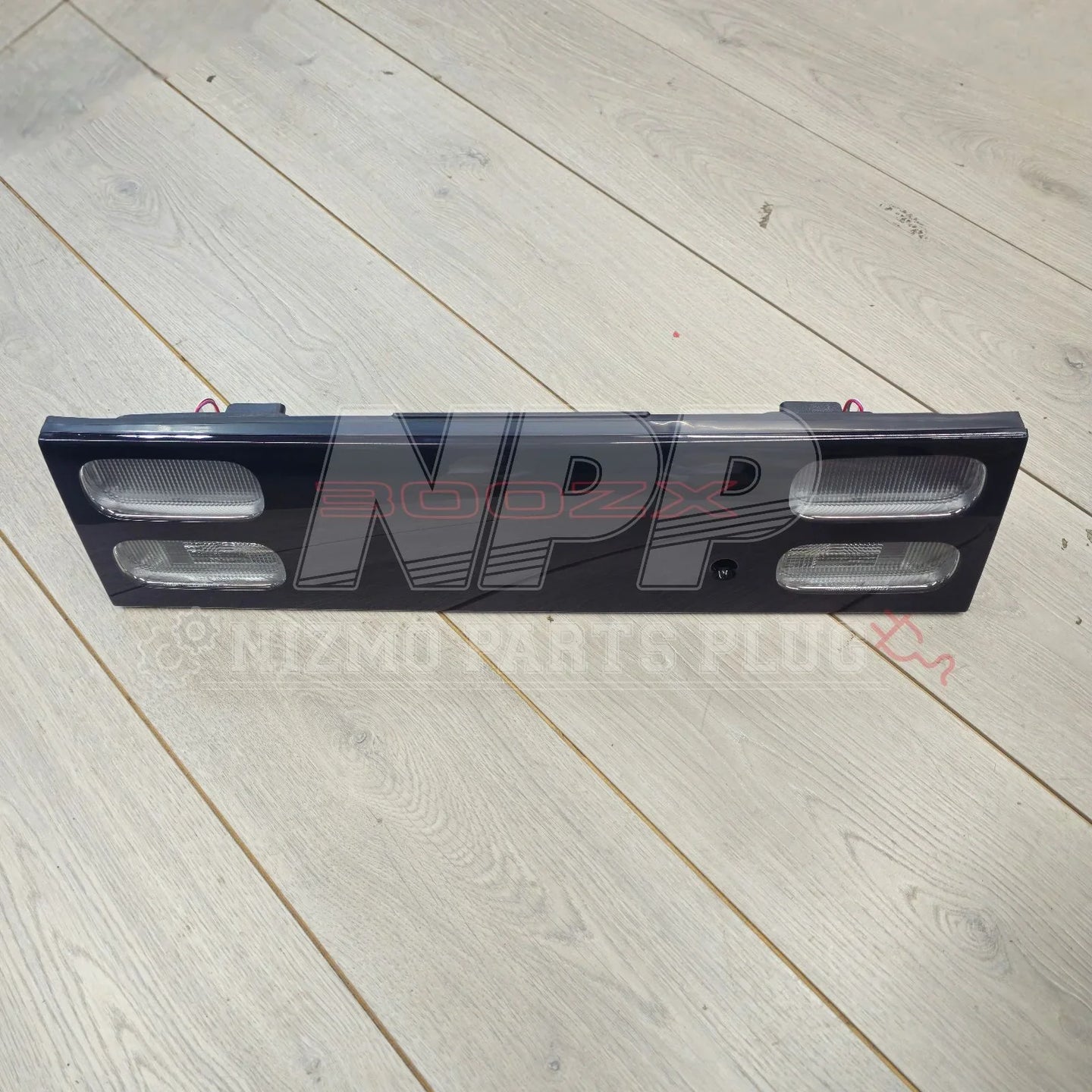 Nissan 300ZX Z32 tail light garnish panel with signal lens on light wood floor