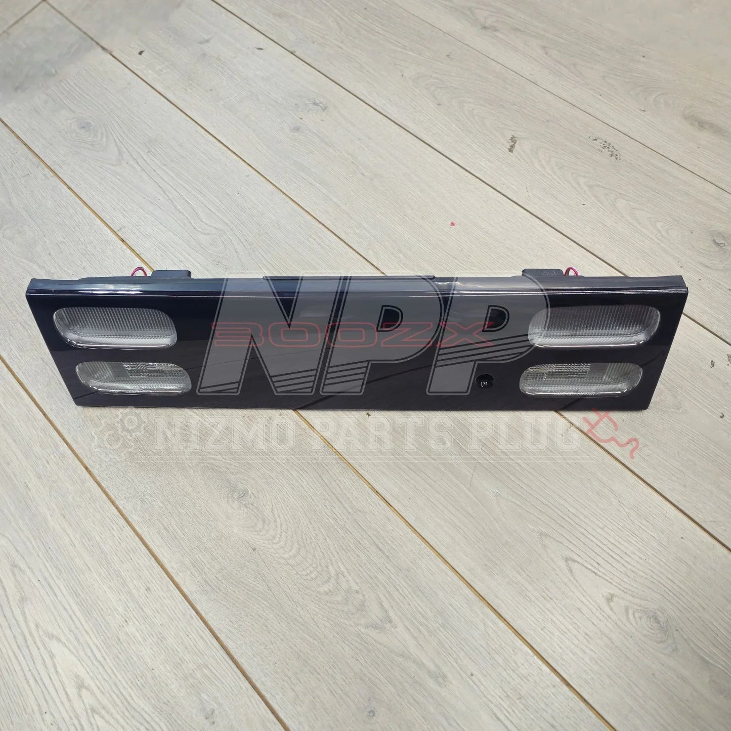 Nissan 300ZX Z32 tail light garnish panel with signal lens on light wood floor