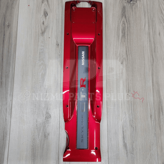 Red car part with Nissan logo on a wooden surface