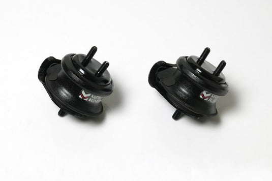 Two black Megan Racing hardened rubber engine mounts for Nissan Skyline R34, shown from side angle.