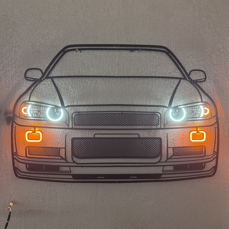Load image into Gallery viewer, Black metal R34 GT-R wall art with glowing white LED headlights and orange neon accent lights.
