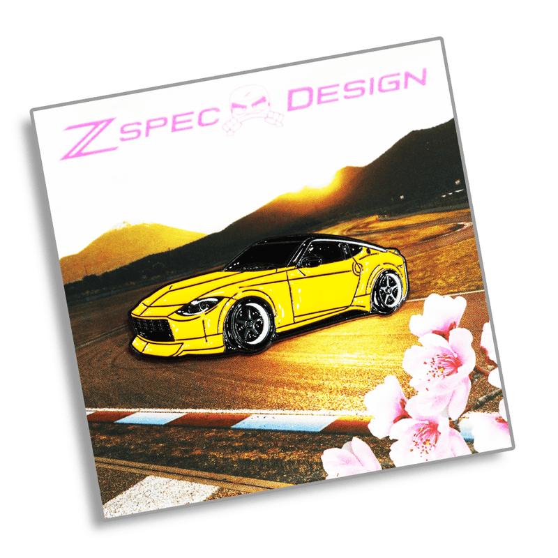 Load image into Gallery viewer, Yellow Nissan Z (RZ34) enamel collector pin featuring a drift track background and cherry blossoms.
