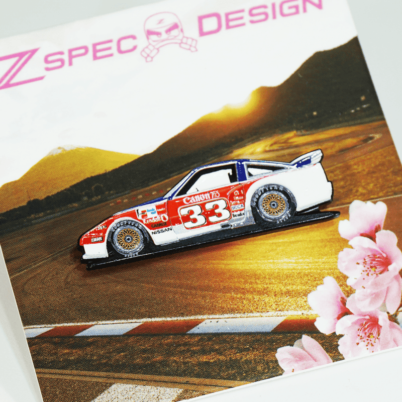 Load image into Gallery viewer, Nissan 300ZX Z31 BSR Newman race car lapel pin, white, red, and blue livery with gold wheels, on display card.
