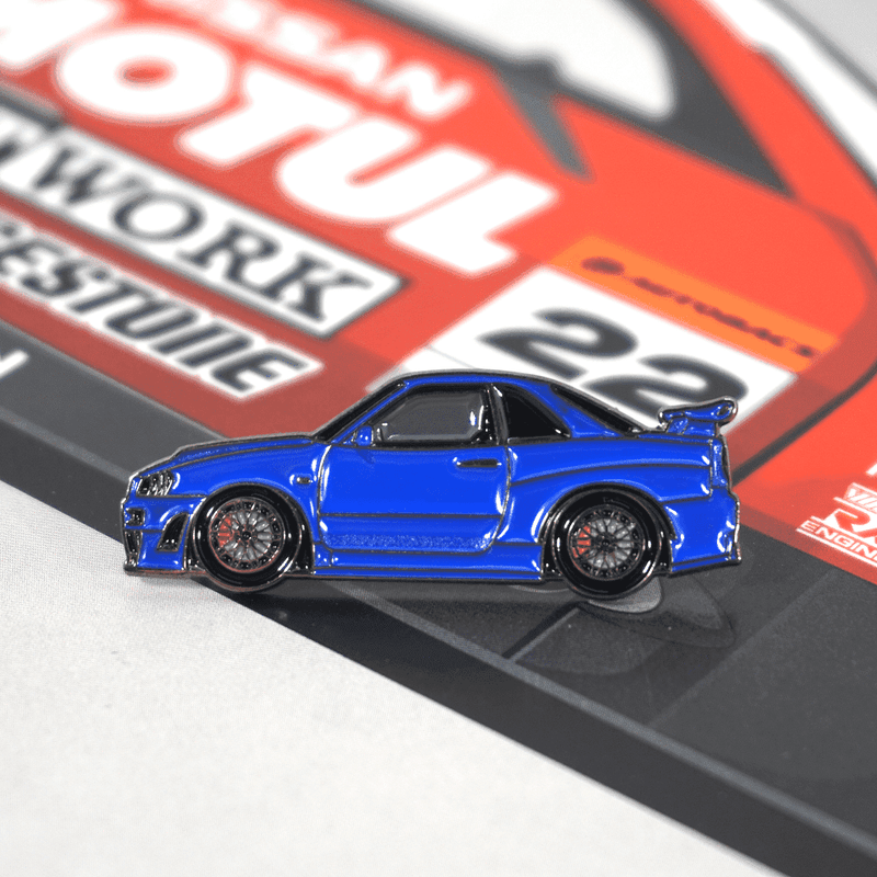 Load image into Gallery viewer, Blue Nissan Skyline GT-R R34 metal lapel pin on a race-themed background.
