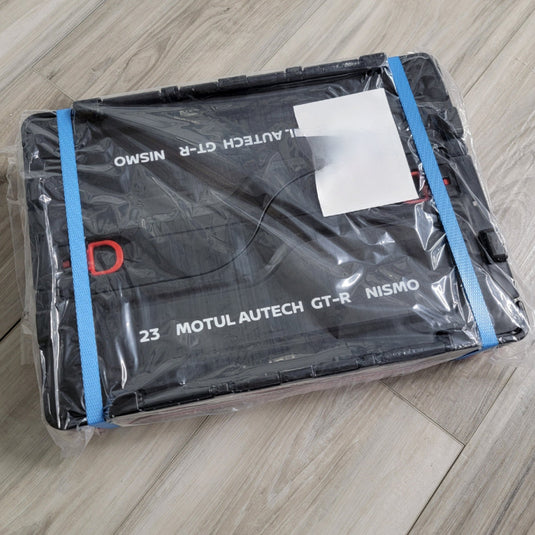 New black Nismo 20L folding container tote for GT-R, sealed in original plastic packaging with blue straps.