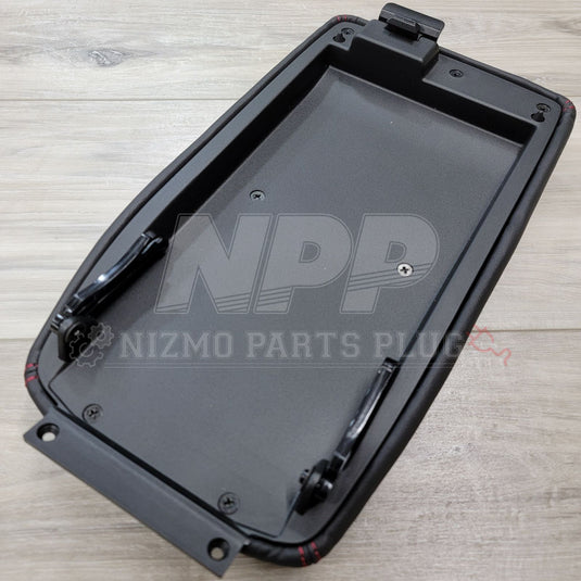Nissan Skyline GTR console lid, black leather with red stitching, underside view with mounting hardware.