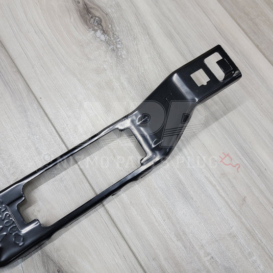 Black metal license plate lamp bracket for Nissan Skyline R34, shown in excellent condition on a wood surface.
